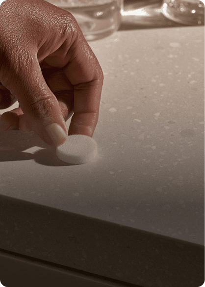 A hand pressing a sample swab onto a kitchen counter